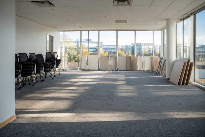 Open space de bureaux vide, chaises empilees et tables demontees avant transfert
