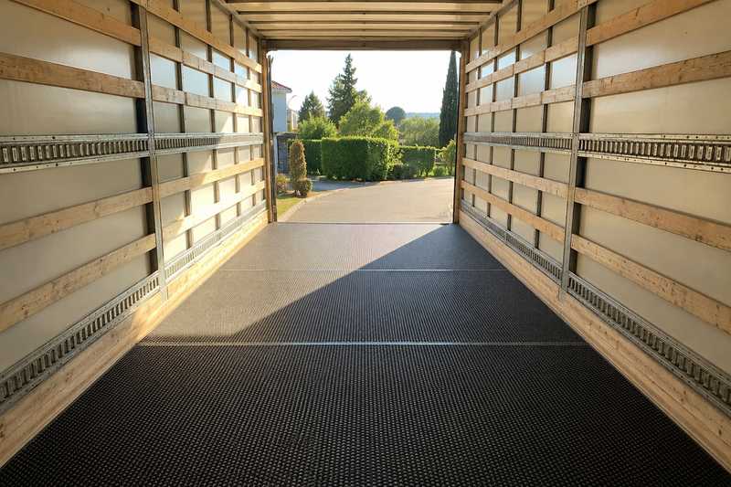 Tapis antiderapants deroules sur le plancher bois d'une caisse de camion vide