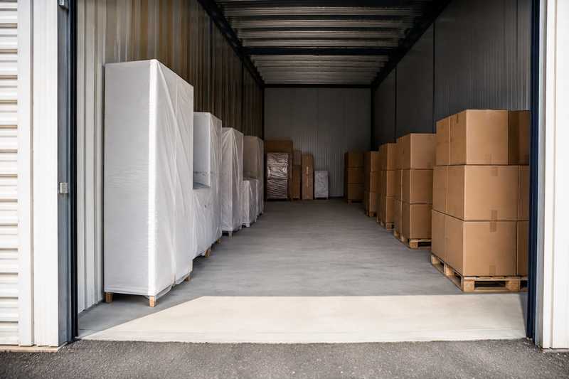 Interieur d'un box de stockage, mobilier housse range contre la paroi et cartons sur palettes