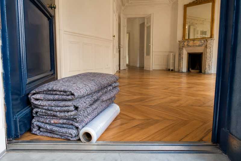 Couvertures matelassees pliees et rouleau de film etirable poses sur le seuil d'une porte paliere